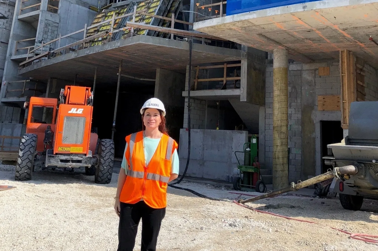 A woman in an orange vest standing on the side of a building.